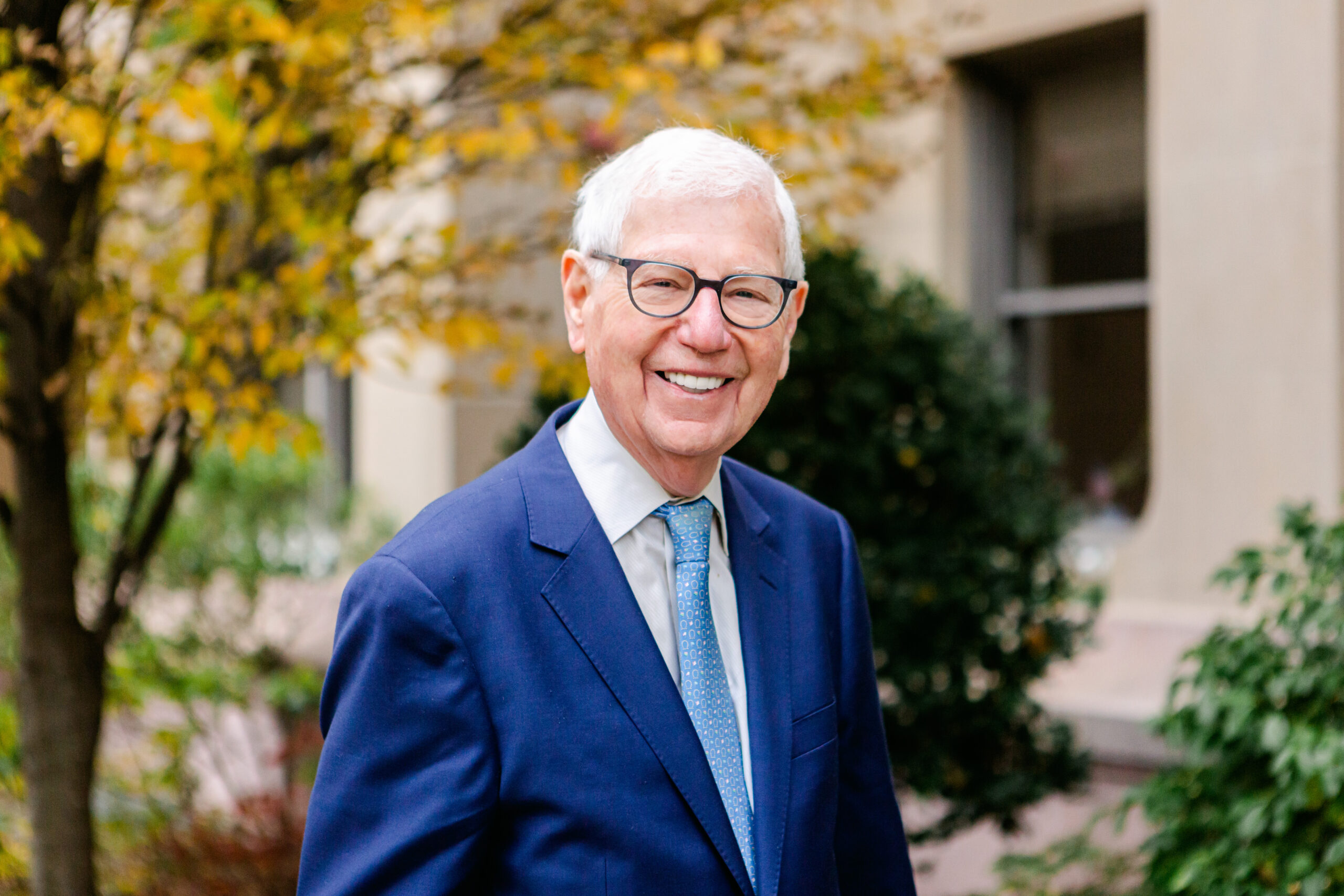 Headshot of Bernard Rosof. Bernard wears glasses and a blue suit and tie.