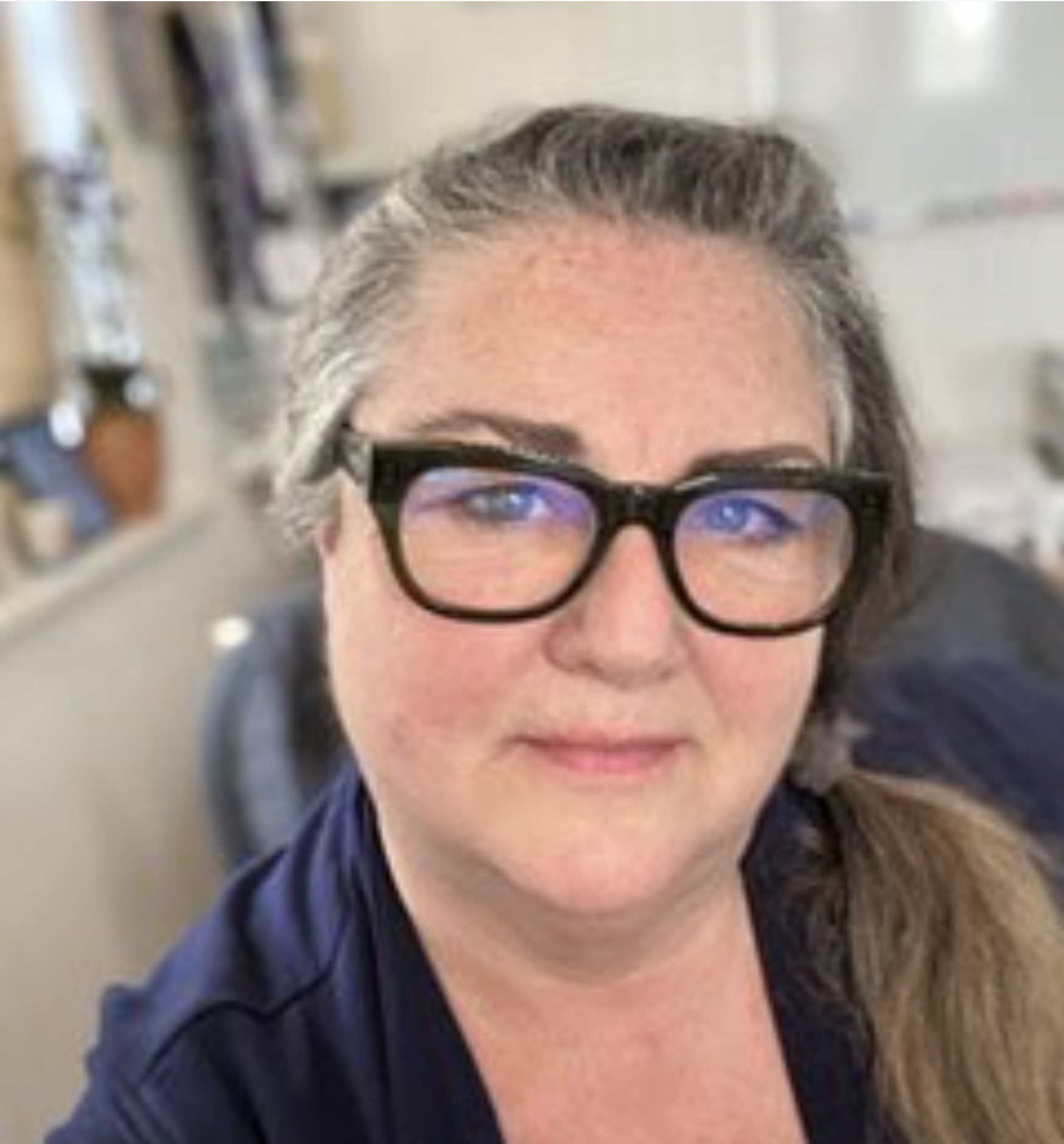 Headshot of Cathy Farmer. Cathy wears black glasses and a navy blue shirt.