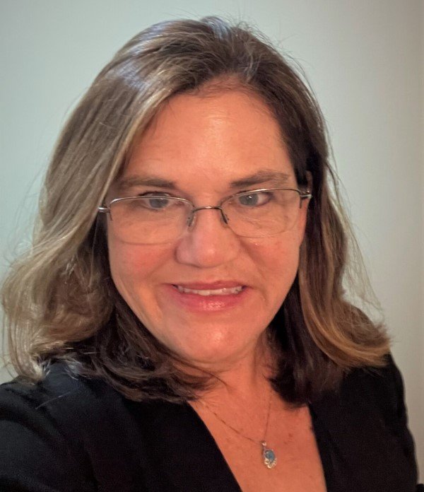 Headshot of Cheryl Powell. Cheryl wears glasses and a black shirt.