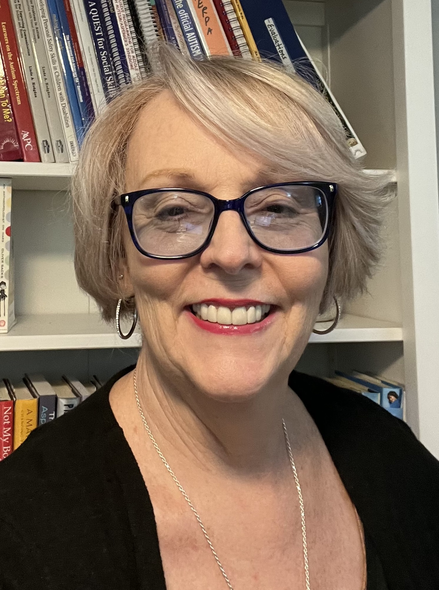 Headshot of Dena Gassner. Dena wears glasses and a black shirt.