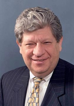 Headshot of Howard Gold. Howard wears a suit and a yellow tie.