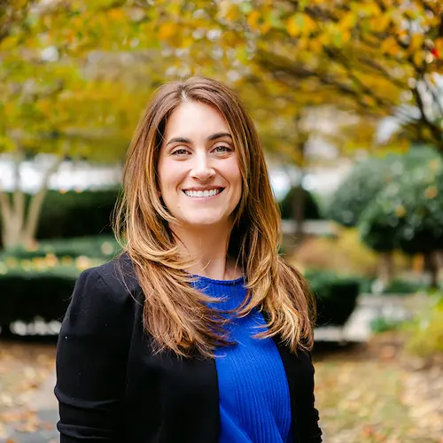 Headshot of Lauren Erickson. Lauren wears a blue shirt and black sweater.