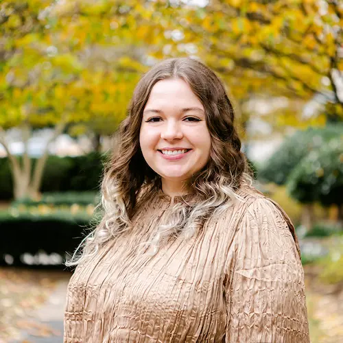 Headshot of Madelyn Bahr. Madelyn wears a tan dress.